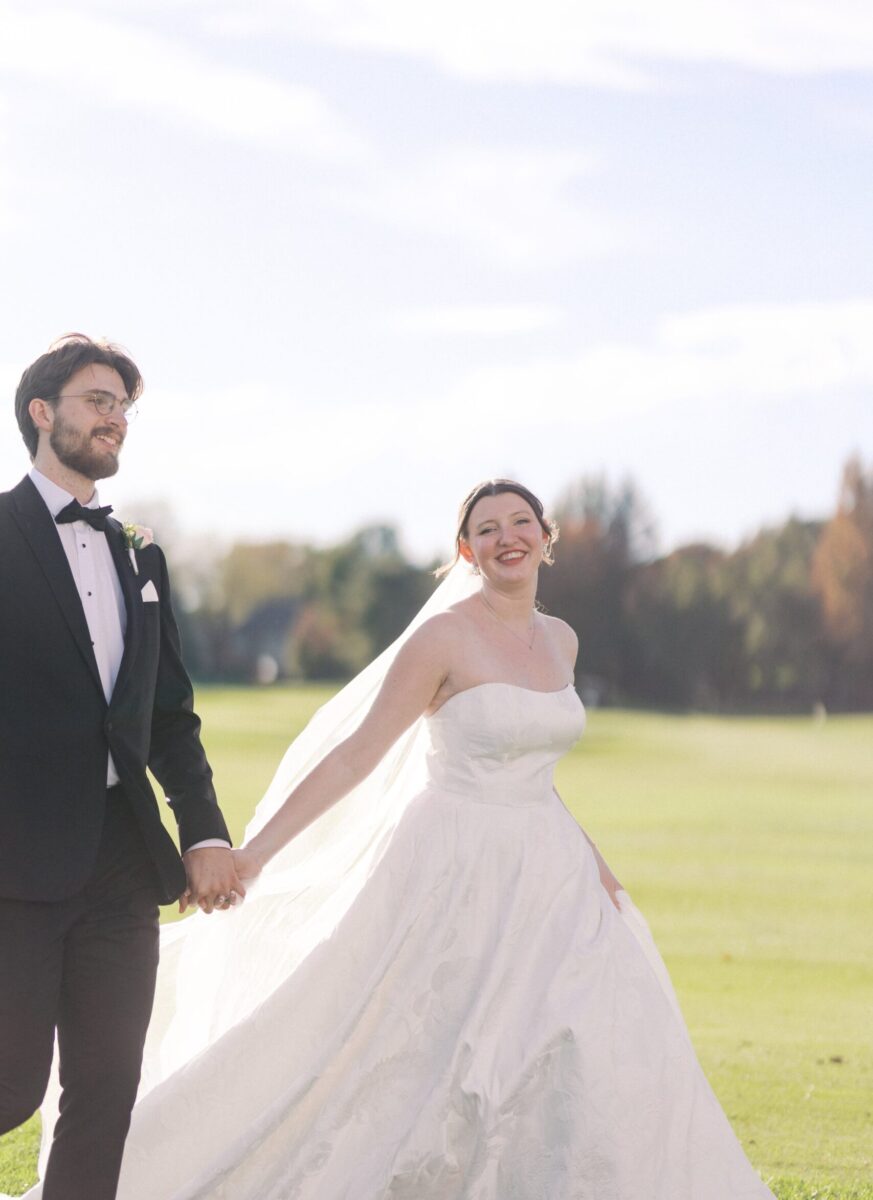 Bride and groom holding hands, walking on the course at Bent Creek Country Club