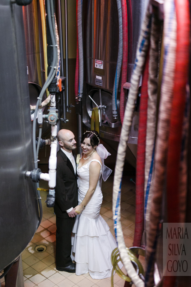 Bride and groom between brewery tanks