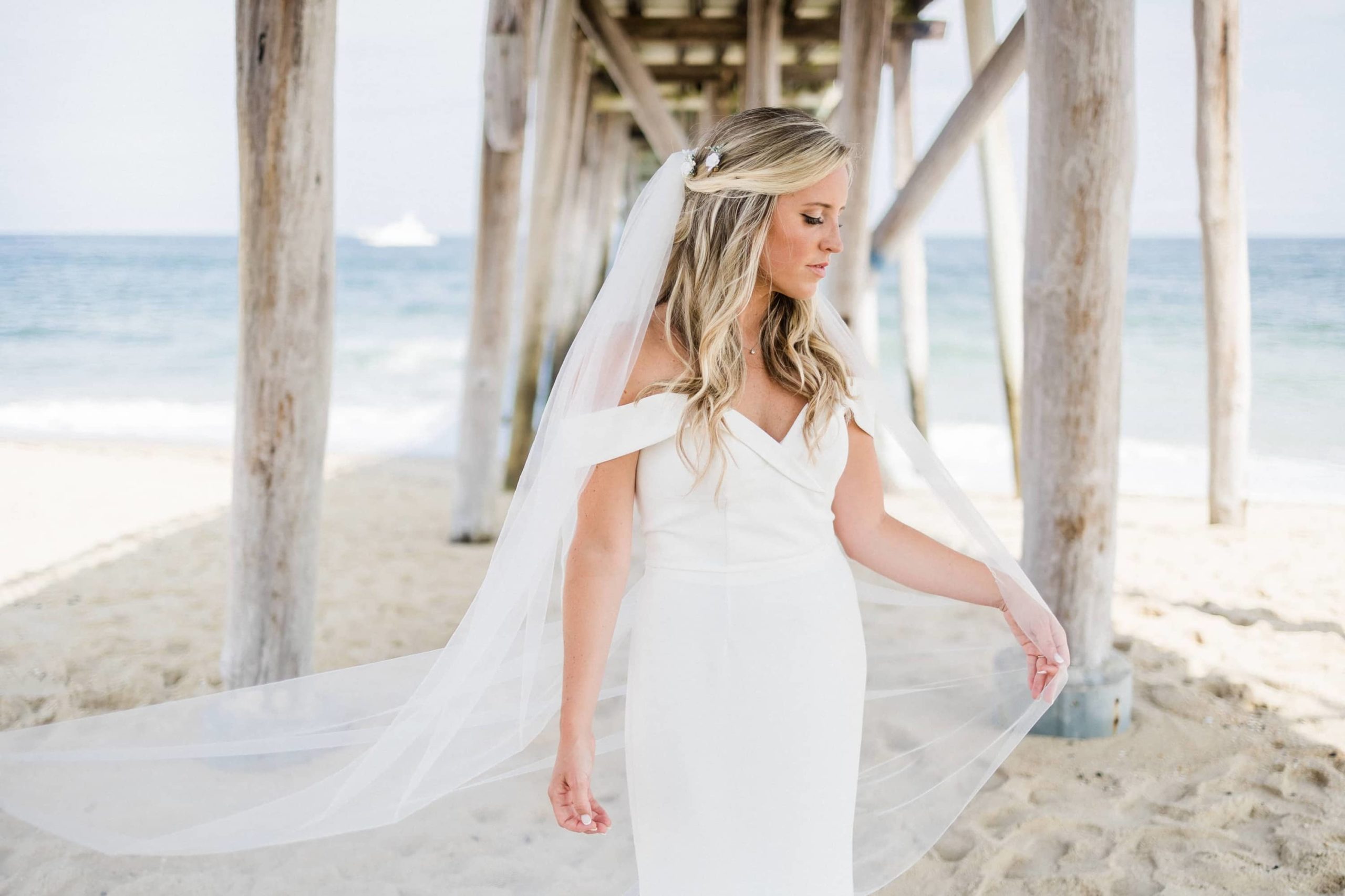 Bride holding veil under the pier of the Belmar Fishing Club in New Jersey
