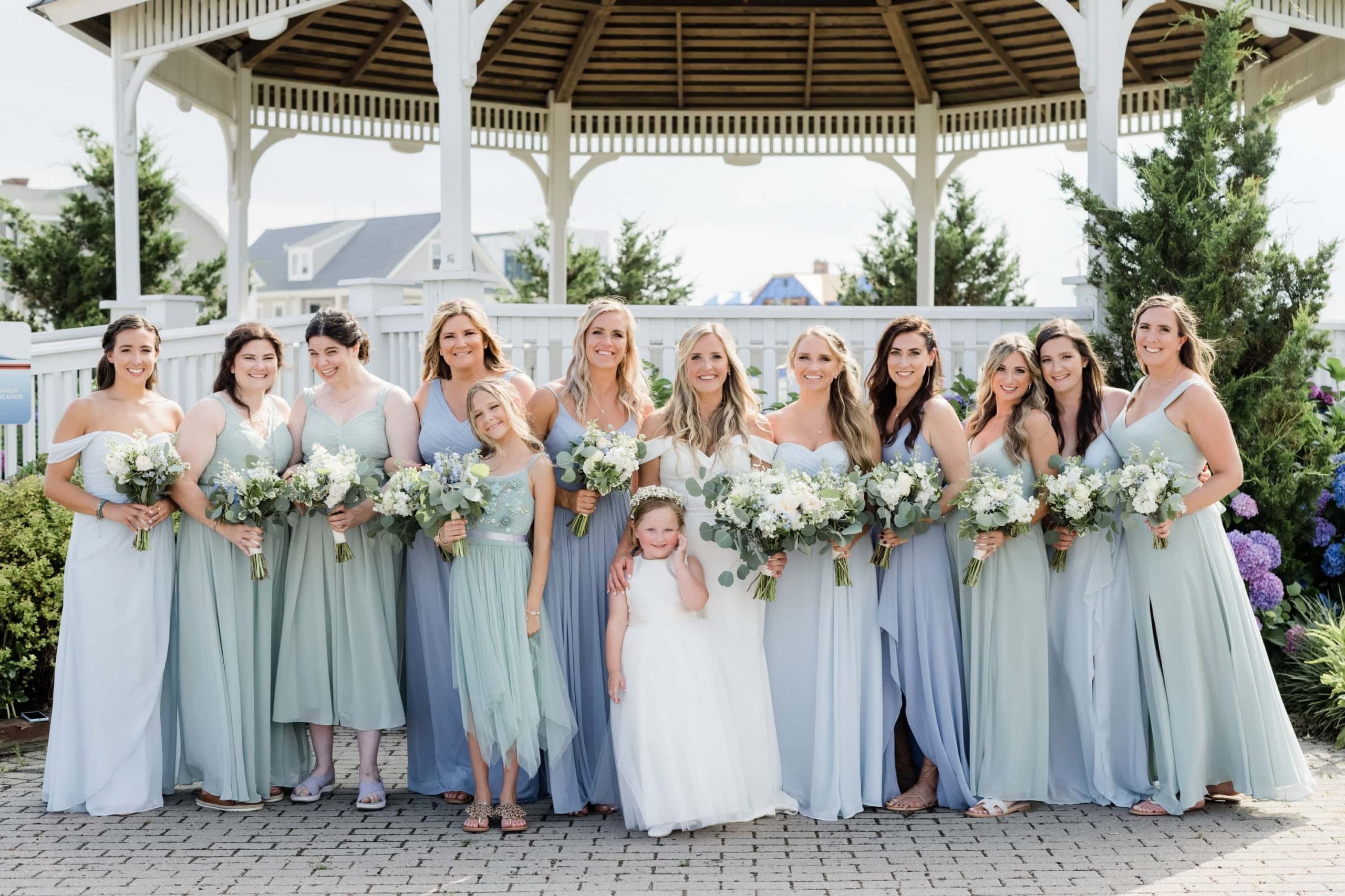 Bride with bridesmaids in light teal, green and blue dresses by the gazebo in Belmar NJ