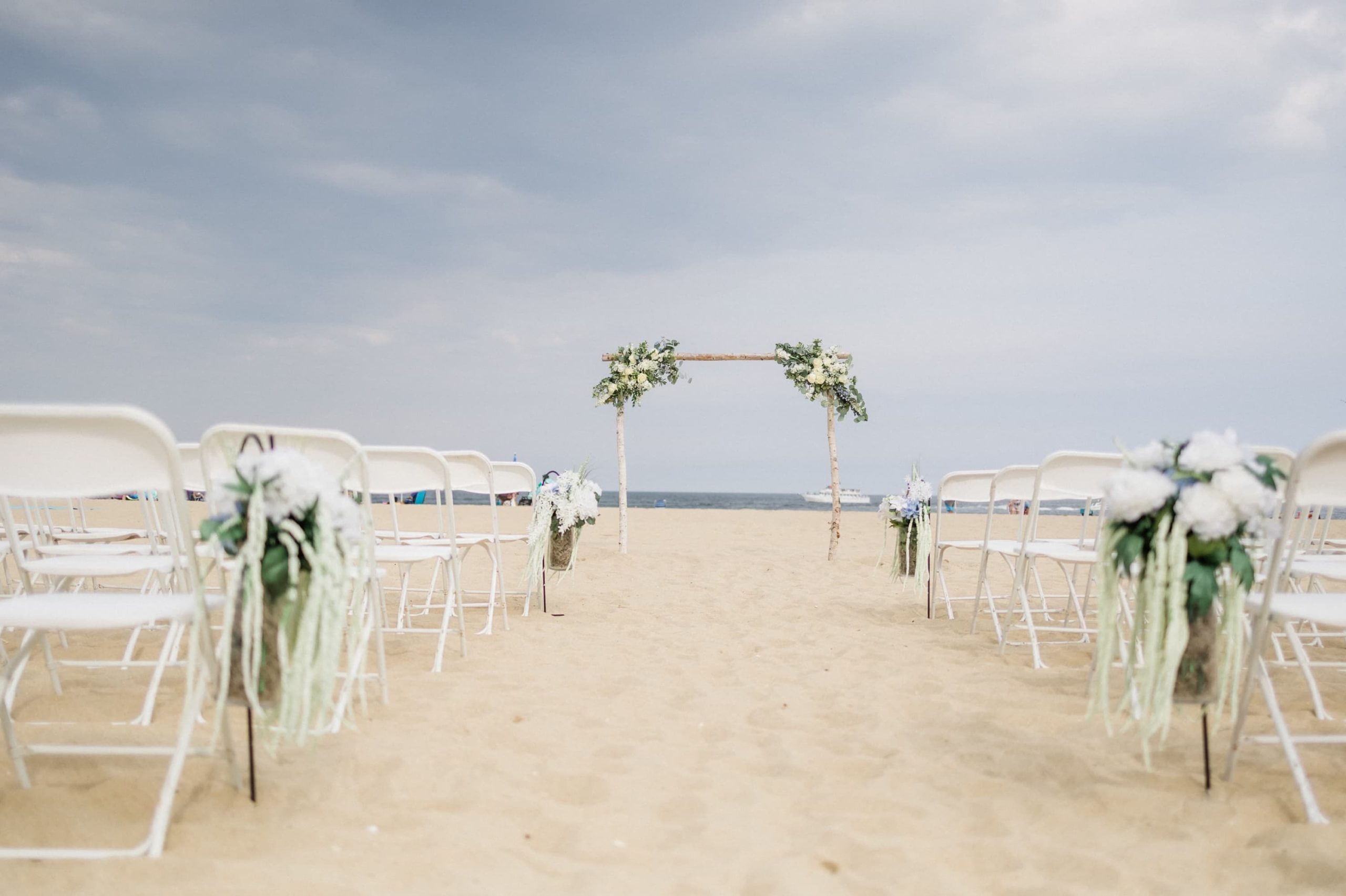 Beach Ceremony set up with wood arch and flowers at the Belmar Taylor Pavilion

