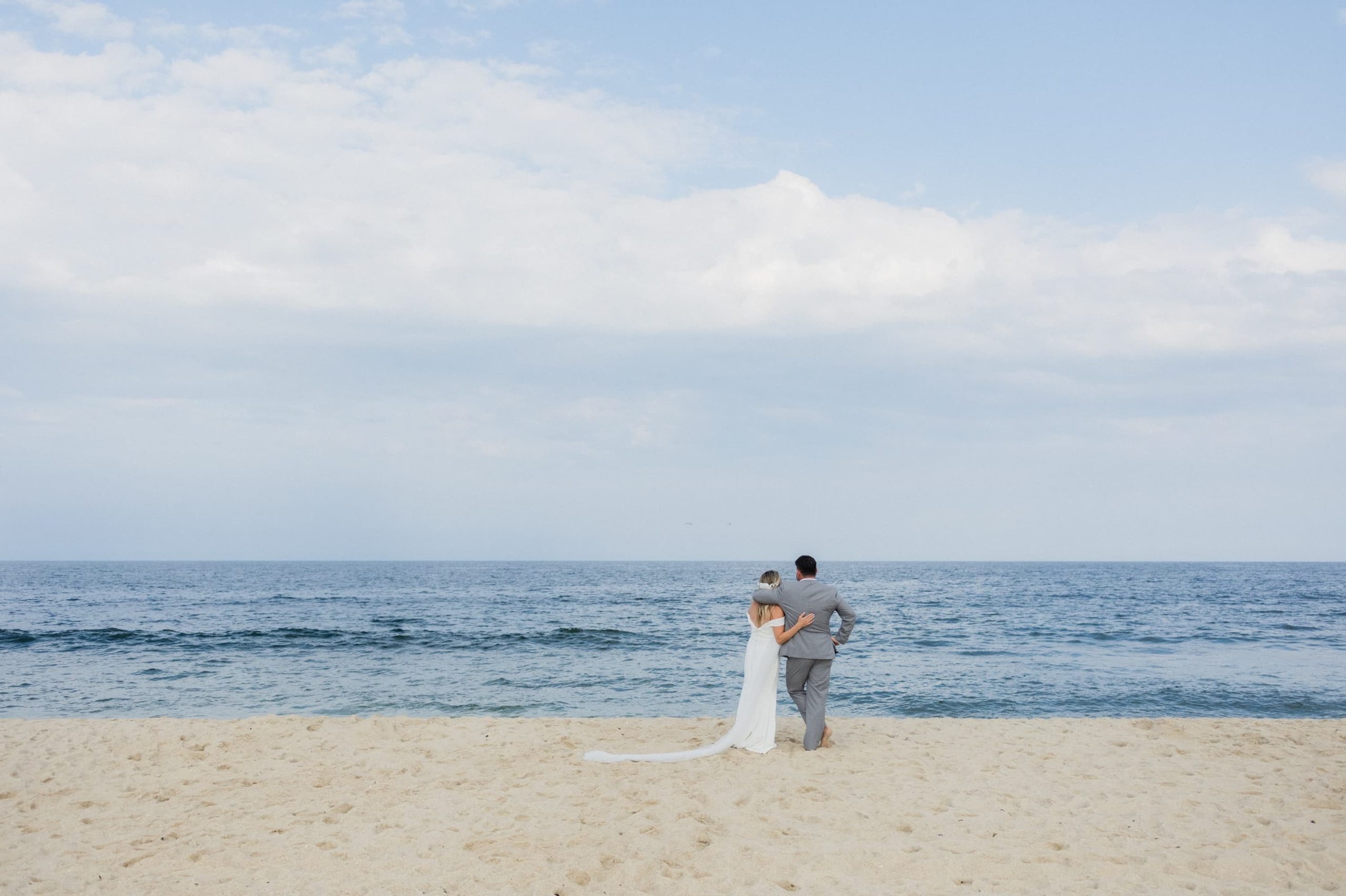 Bride and groom looking at the ocean after their beach wedding