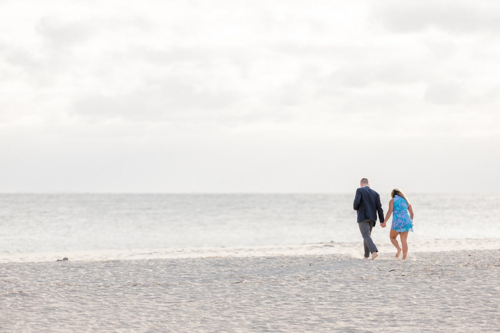 Couple walking towards writing on the sand for beach proposal in Cape May