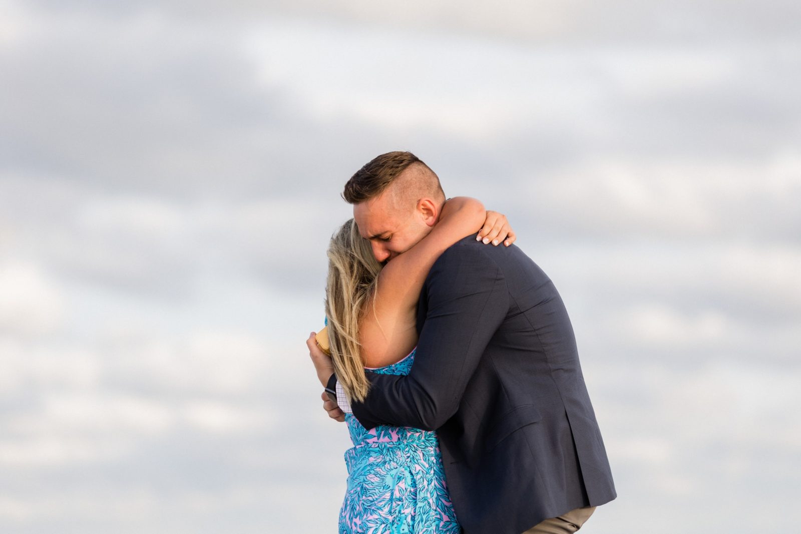 Couple hugging during emotional beach proposal in Cape May
