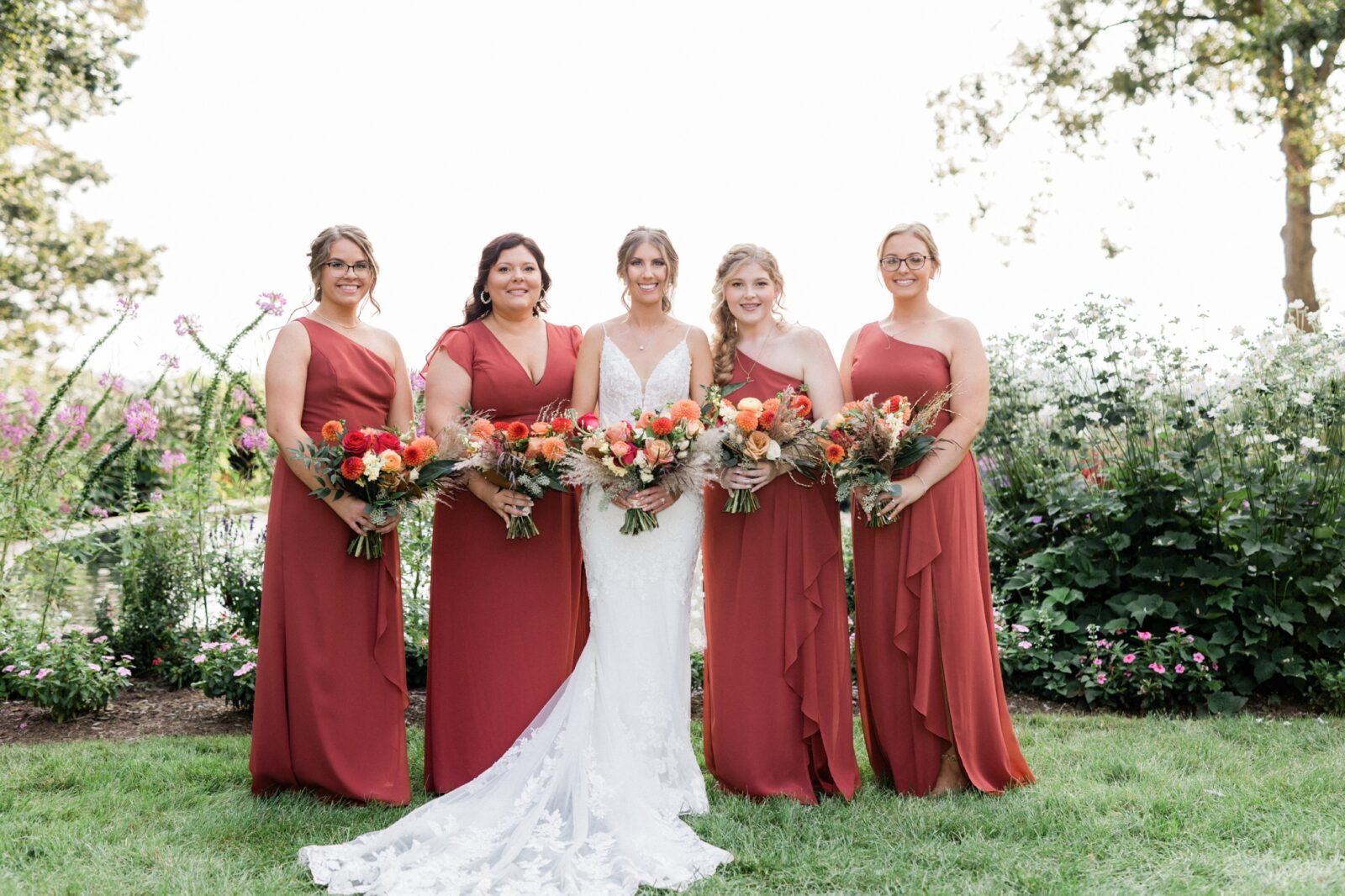 Bride and bridesmaids in coral dresses in the Box Hill Mansion gardens