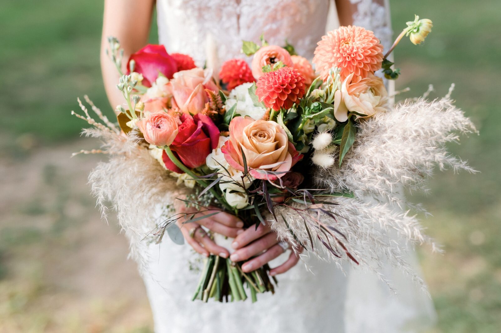 Closeup of fall wedding bouquet with roses, dahlias and ranunculus in shades of coral framed with pampas grass. - Box Hill Mansion wedding by Maria Silva Goyo