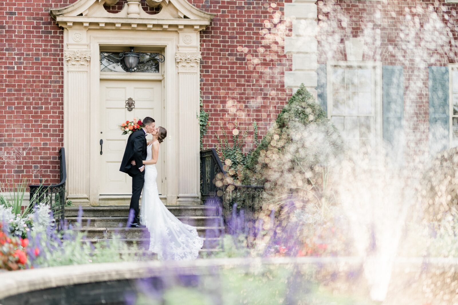 Bride and groom kissing by the mansion with the fountain in the foreground at Box Hill Mansion photographed by Maria Silva Goyo