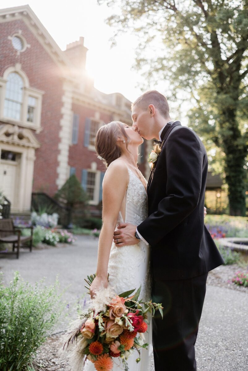 Bride and groom kissing behind the mansion