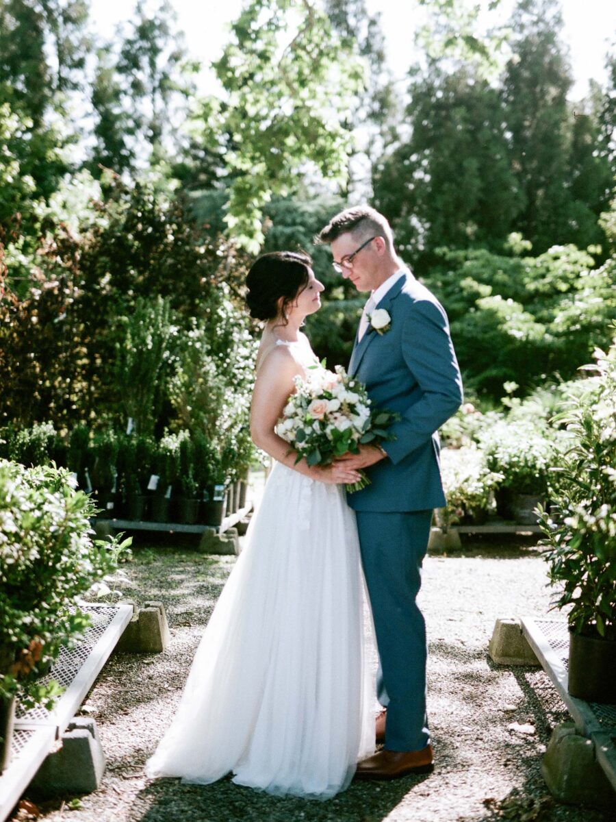 35mm film backlit portrait of the bride and groom among the greenery at Terrain at Styer's holding the bridal bouquet