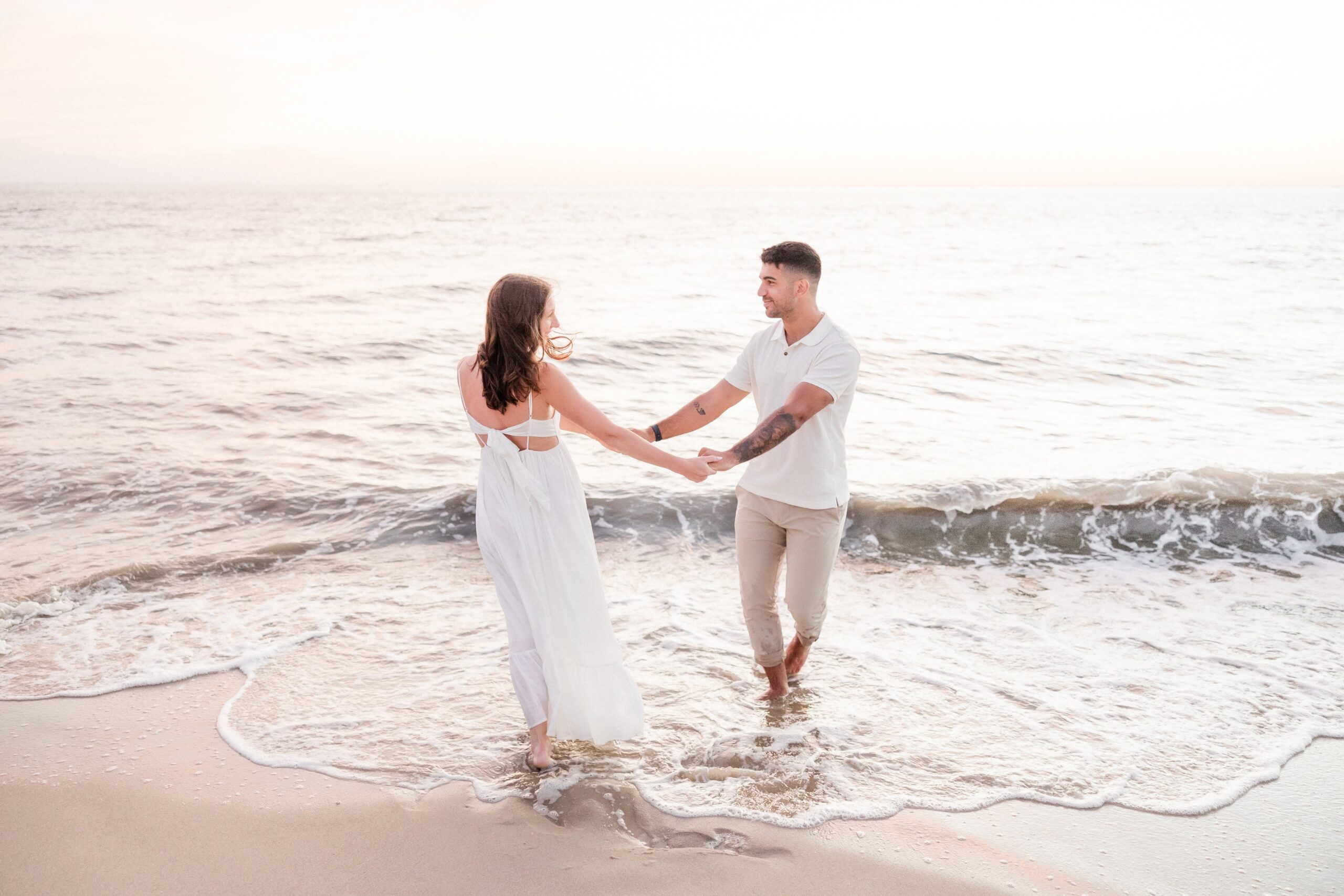 Couple holding hands with their feet in the water at Sunset Beach in Cape May NJ