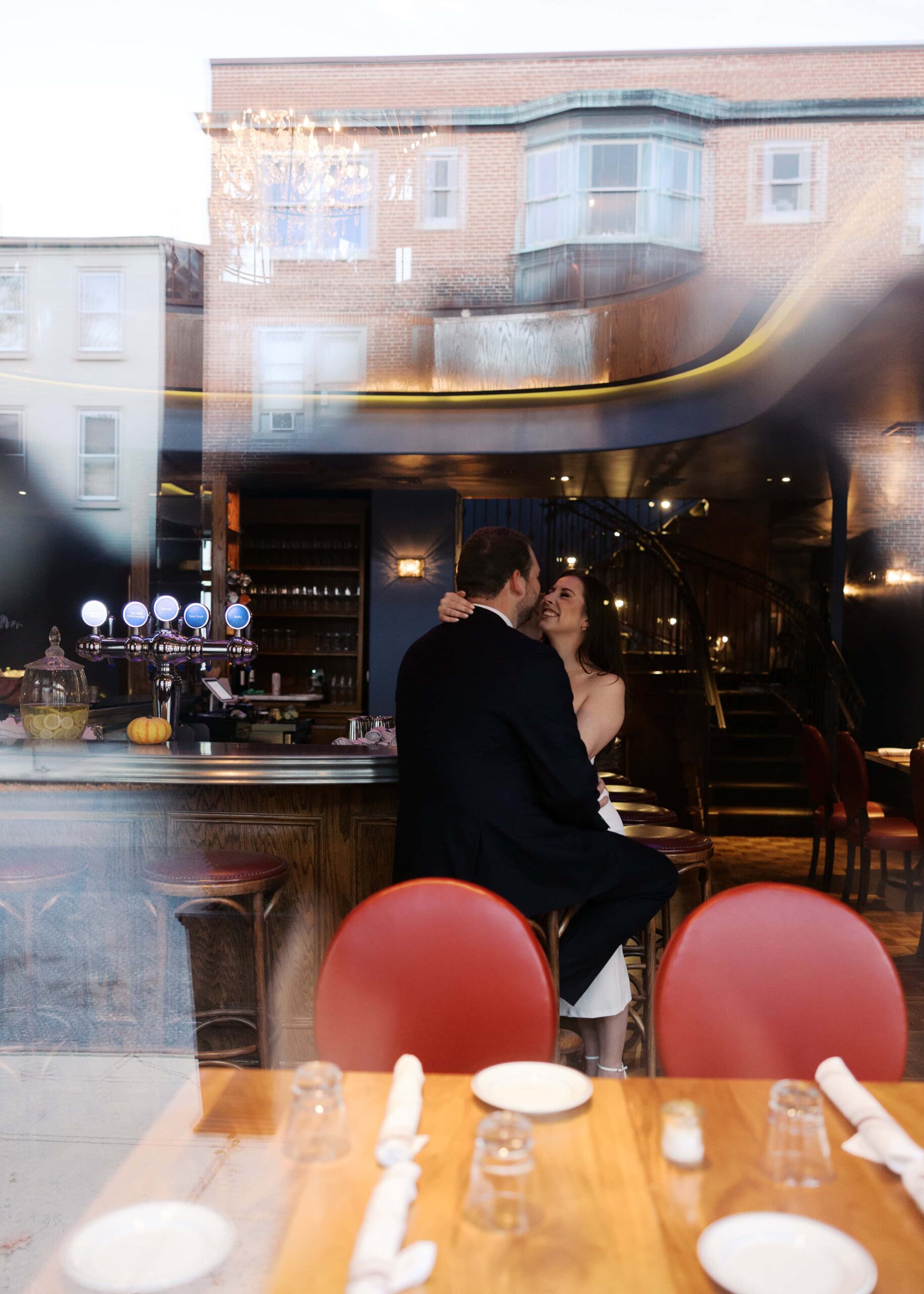 couple sitting inside a bar, photographed from outside the window through the reflections